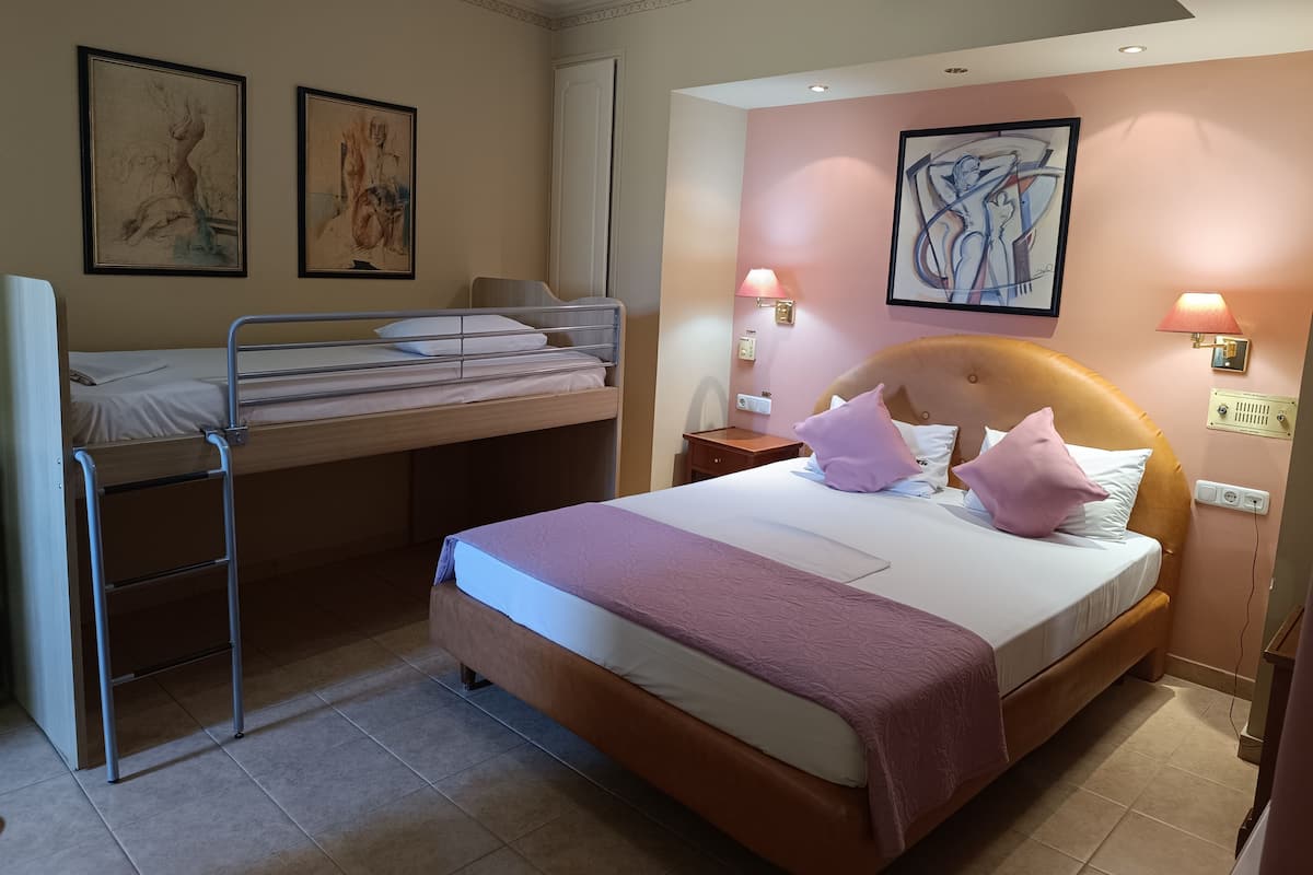A hotel room with a bunk bed, a single bed, and two wall-mounted lamps.