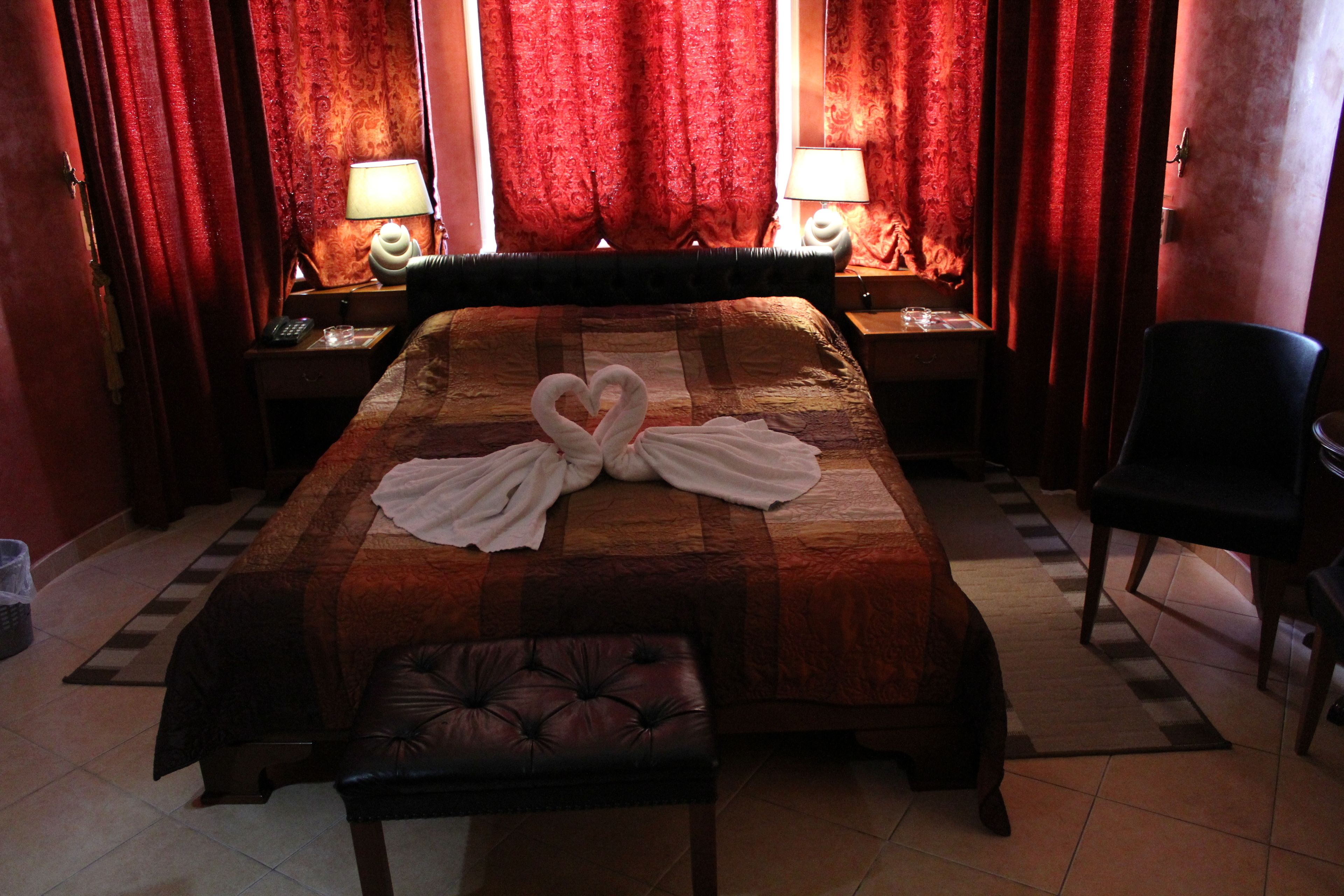 Une chambre d’hôtel avec un grand lit, deux tables de chevet avec des lampes, une chaise et un banc.