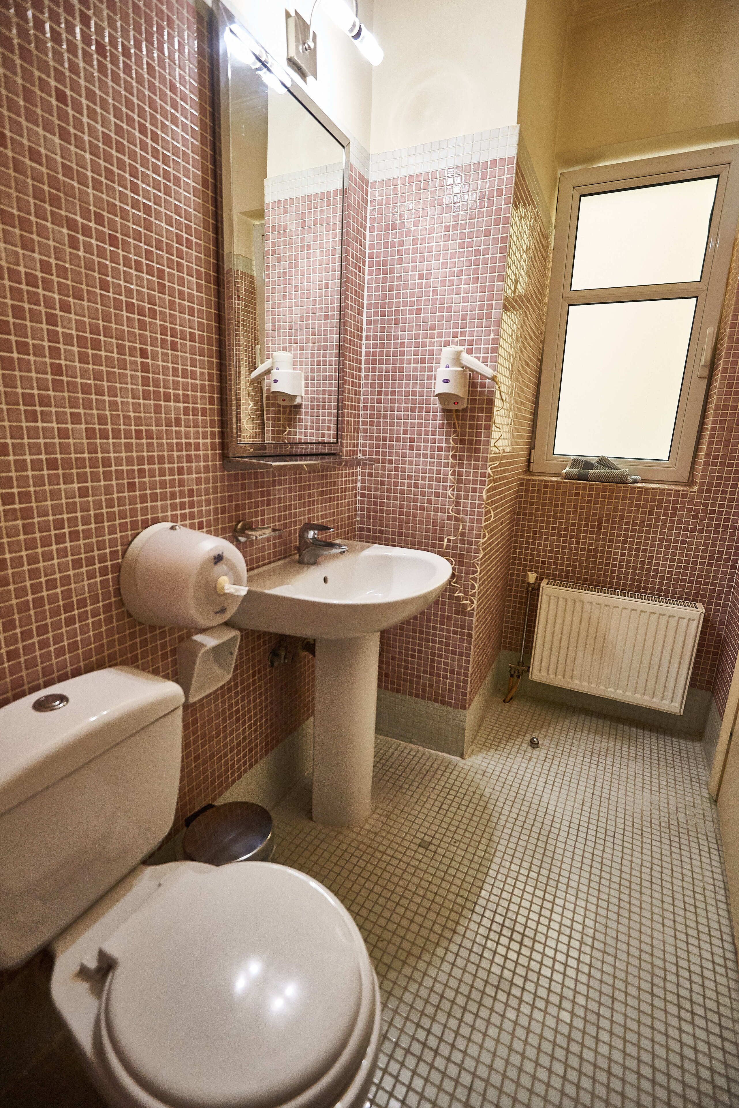 A bathroom with a toilet, sink, and mirror.