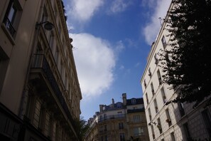 A narrow street between buildings with balconies and a clear sky above. - District République (Paris)