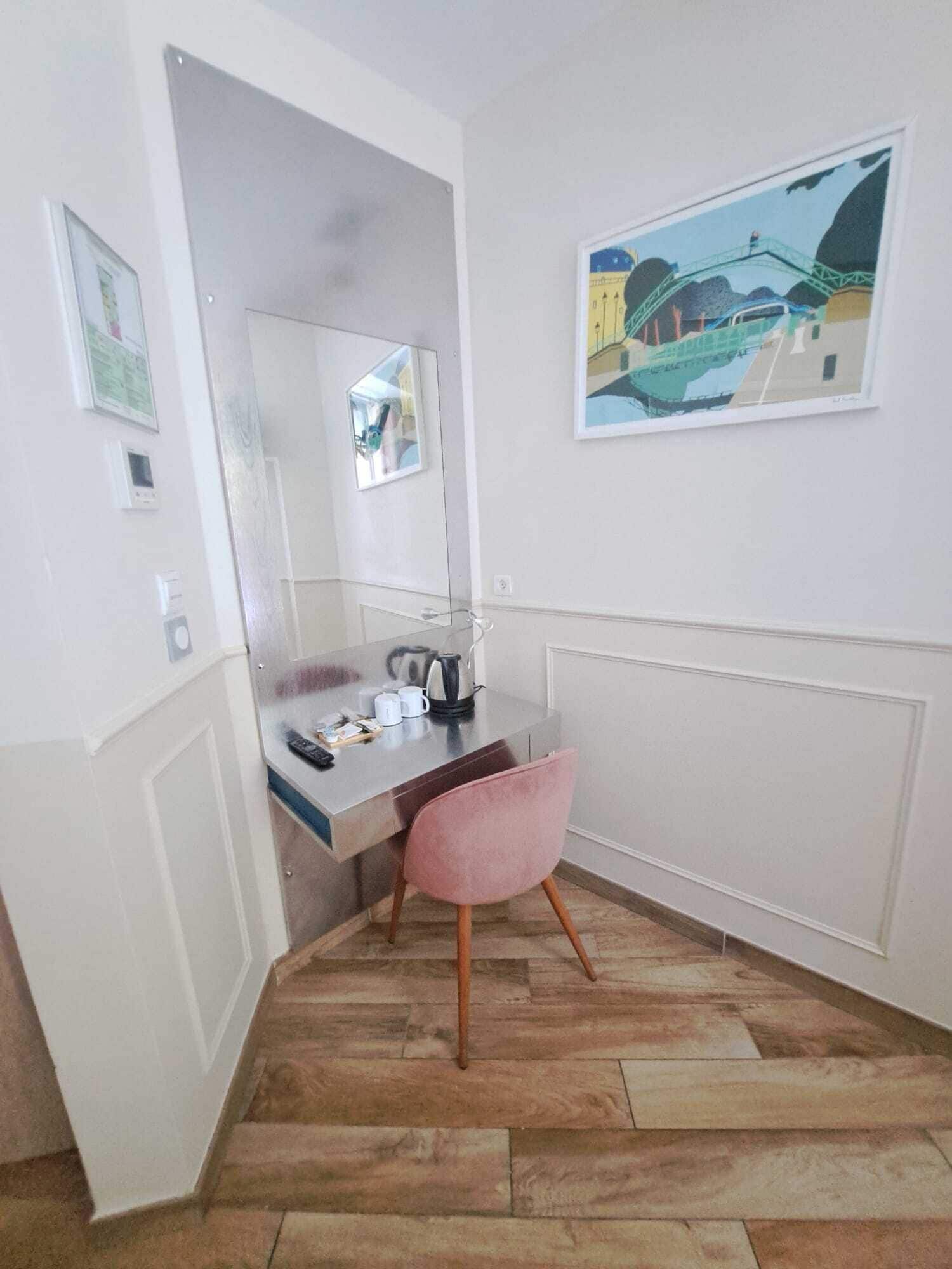 A small, modern room with a desk, chair, and a painting on the wall.