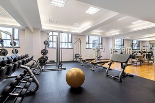 A gym with various exercise equipment, including dumbbells, a bench, and a medicine ball.