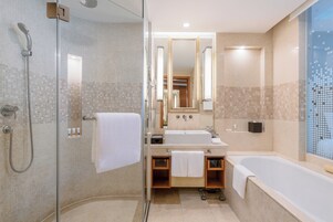 A modern bathroom with a glass-enclosed shower, a large mirror, a bathtub, and a sink with a vanity.
