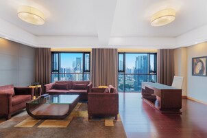 A spacious living room with a city view, a glass coffee table, and a desk with a chair.