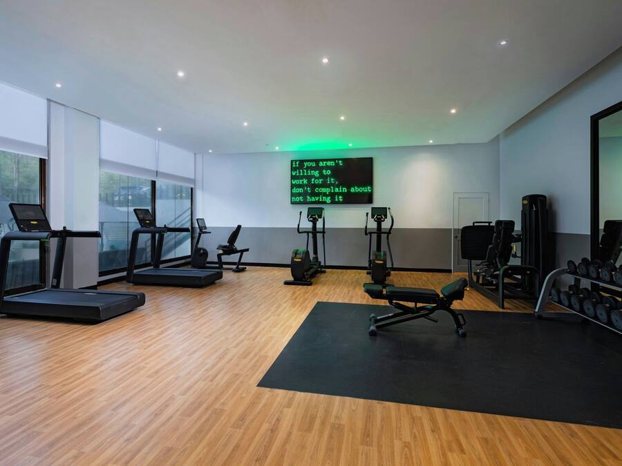Un gimnasio moderno con cintas de correr, máquinas de pesas y una frase motivacional en la pared.