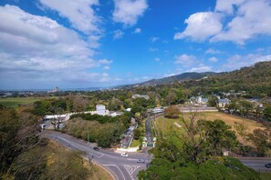 Une vue panoramique d’une ville avec une route sinueuse, des collines verdoyantes et des bâtiments dispersés.