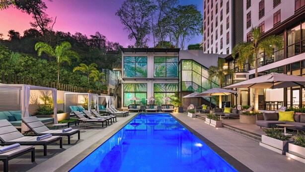 A modern hotel with a pool area, lounge chairs, and outdoor seating. - The BRIX, Autograph Collection (Port of Spain)