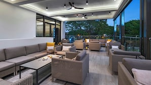 A modern outdoor lounge area with a variety of seating options, including sofas and chairs, arranged around a central coffee table. - The BRIX, Autograph Collection (Port of Spain)
