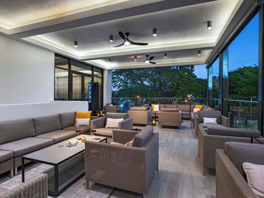 A modern outdoor lounge area with a variety of seating options, including sofas and chairs, arranged around a central coffee table.