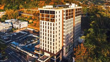 A high-rise hotel with a modern design, featuring a prominent glass facade and a rooftop terrace.