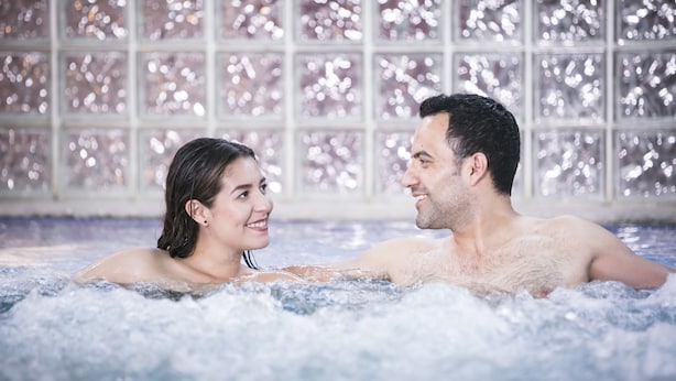 A couple in a hot tub with a decorative tiled wall in the background. - Los Olivos Spa (Oaxaca)