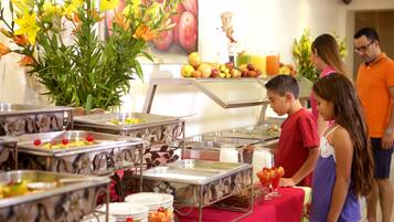 Montaje de bufé con distintas estaciones de comida y una decoración floral.