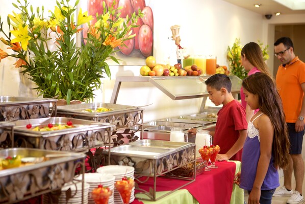 Montaje de bufé con distintas estaciones de comida y una decoración floral.