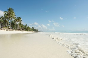 Na praia, areia branca, guarda-sóis, toalhas de praia 
