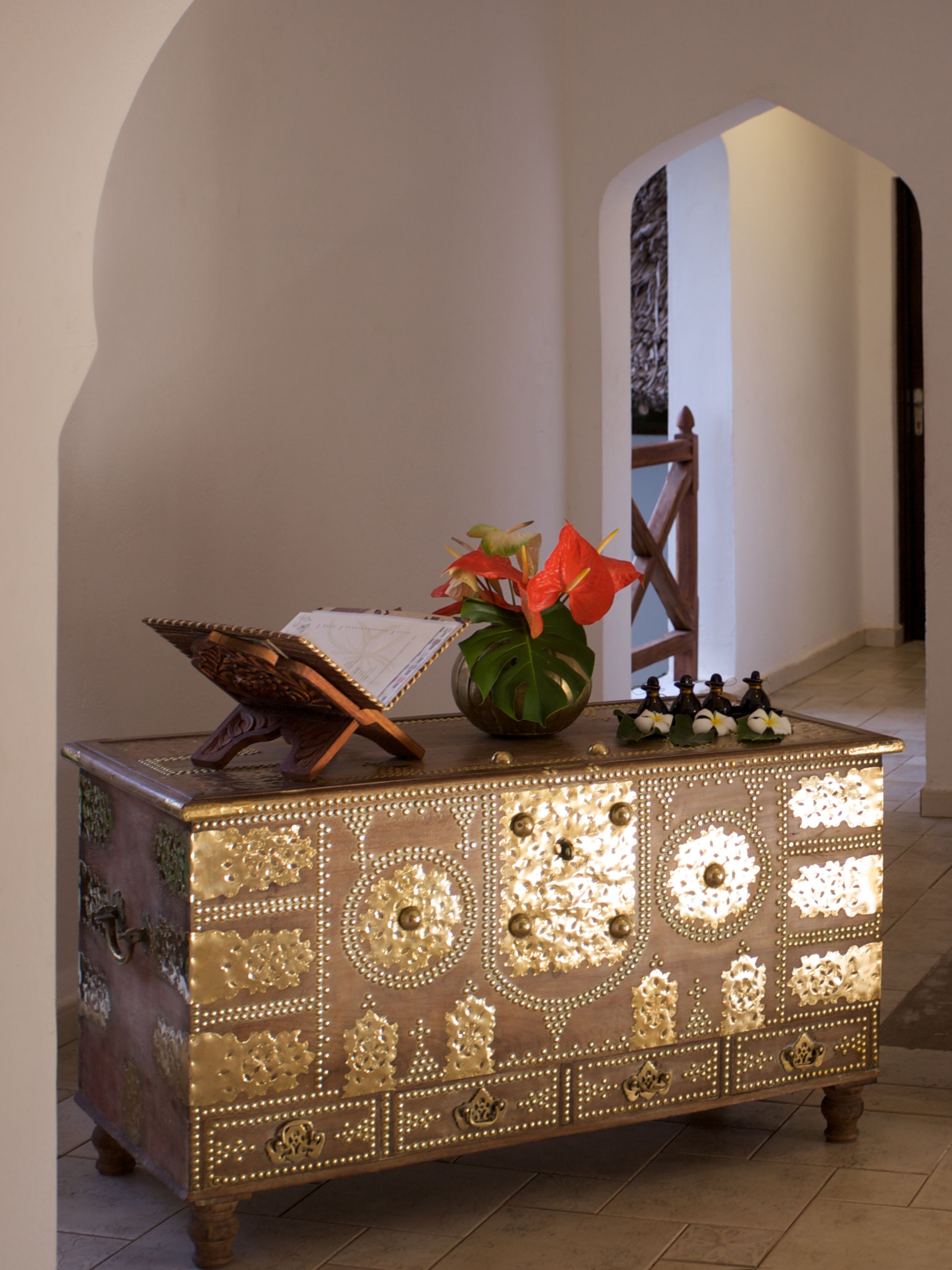 Un cofre de madera decorativo con diseños intrincados y un jarrón con flores encima.