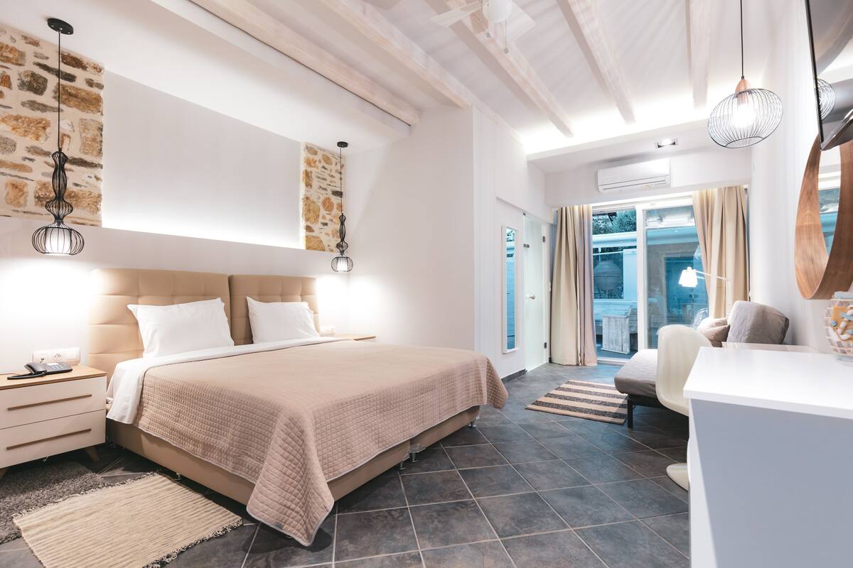 A modern bedroom with a large bed, bedside tables, a desk, and a view of the outdoors.