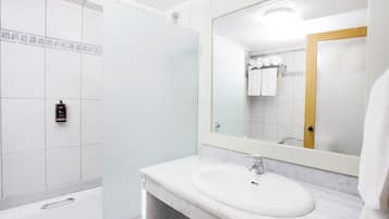 Un baño con lavamanos blanco, espejo y zona de ducha.