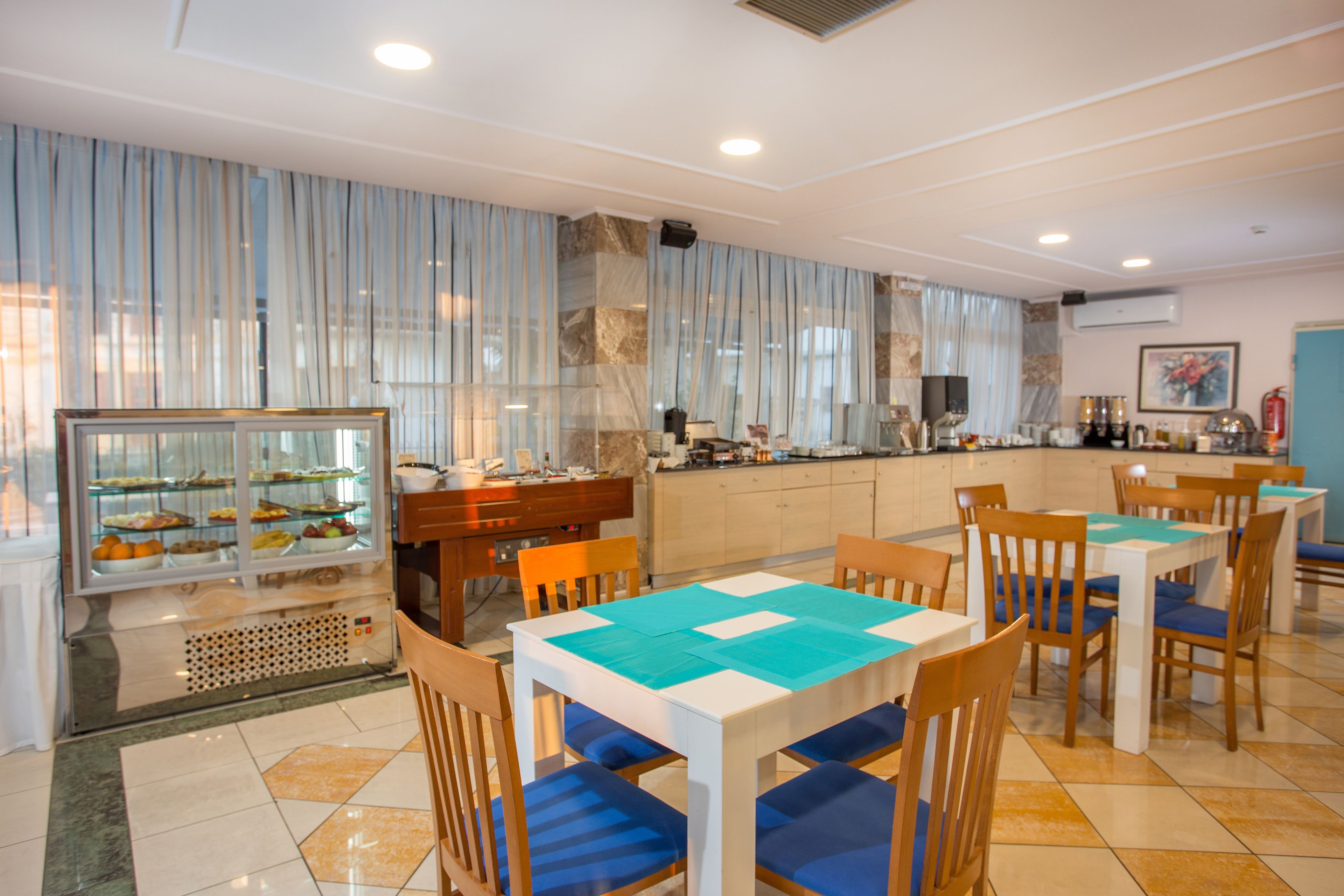A restaurant with a buffet, wooden tables, and chairs.