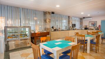 A restaurant with a buffet, wooden tables, and chairs.