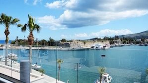 A marina with boats docked, palm trees, and a clear sky.