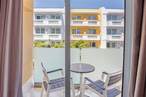 A balcony with two chairs and a table, overlooking a yellow building with multiple balconies. - Kosta Palace (Kos)