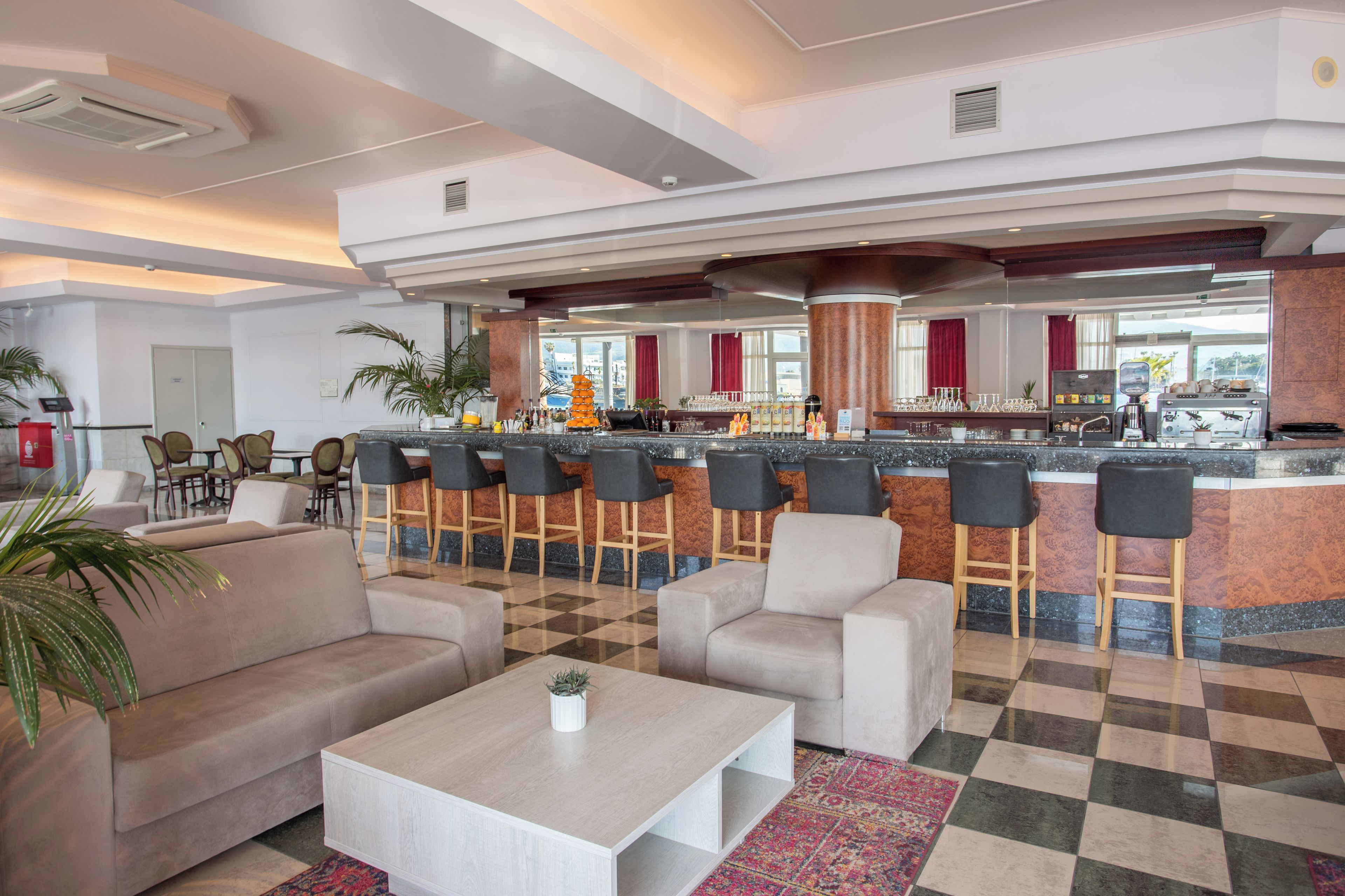 A hotel lobby with a bar area, seating, and a check-in desk.