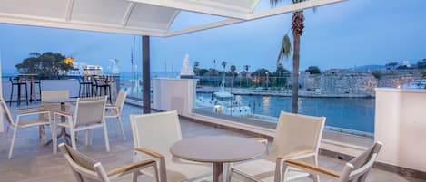 A terrace with white furniture, a view of the sea, and a statue.