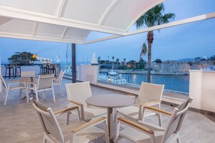 Una terraza con mobiliario blanco, vista al mar y una estatua.