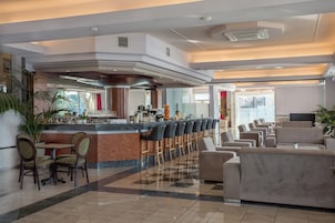 Un vestíbulo de hotel con una zona de bar, asientos y un mostrador de recepción.