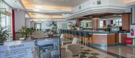 Un hall de hotel con mostrador de recepción, zona de estar y un bar.