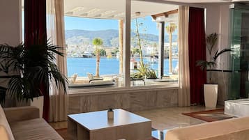 Un'ampia zona giorno con vista sul mare e sulle montagne, arredata con divani e un tavolino da caffè.