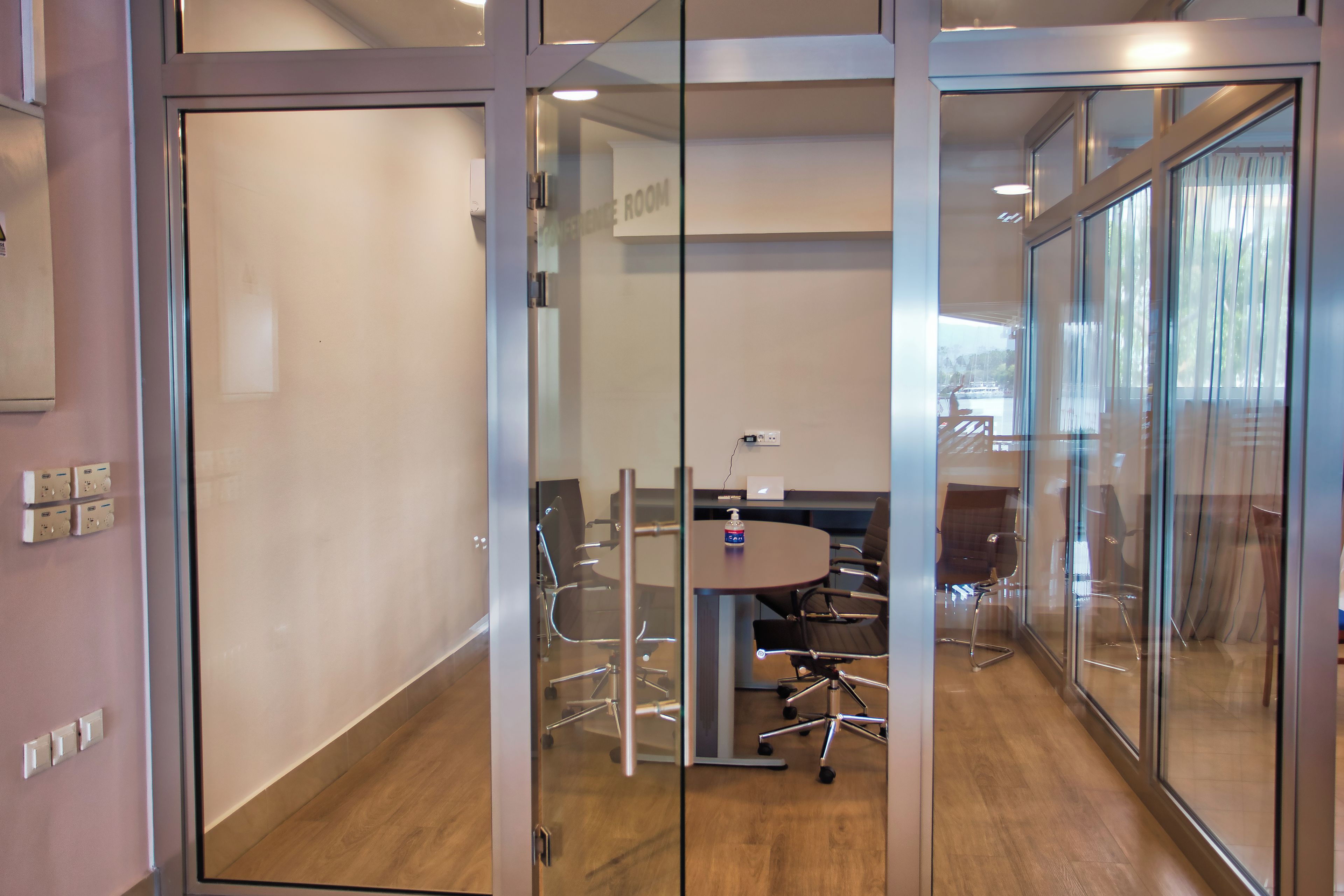 A modern conference room with glass walls, a round table, and office chairs.