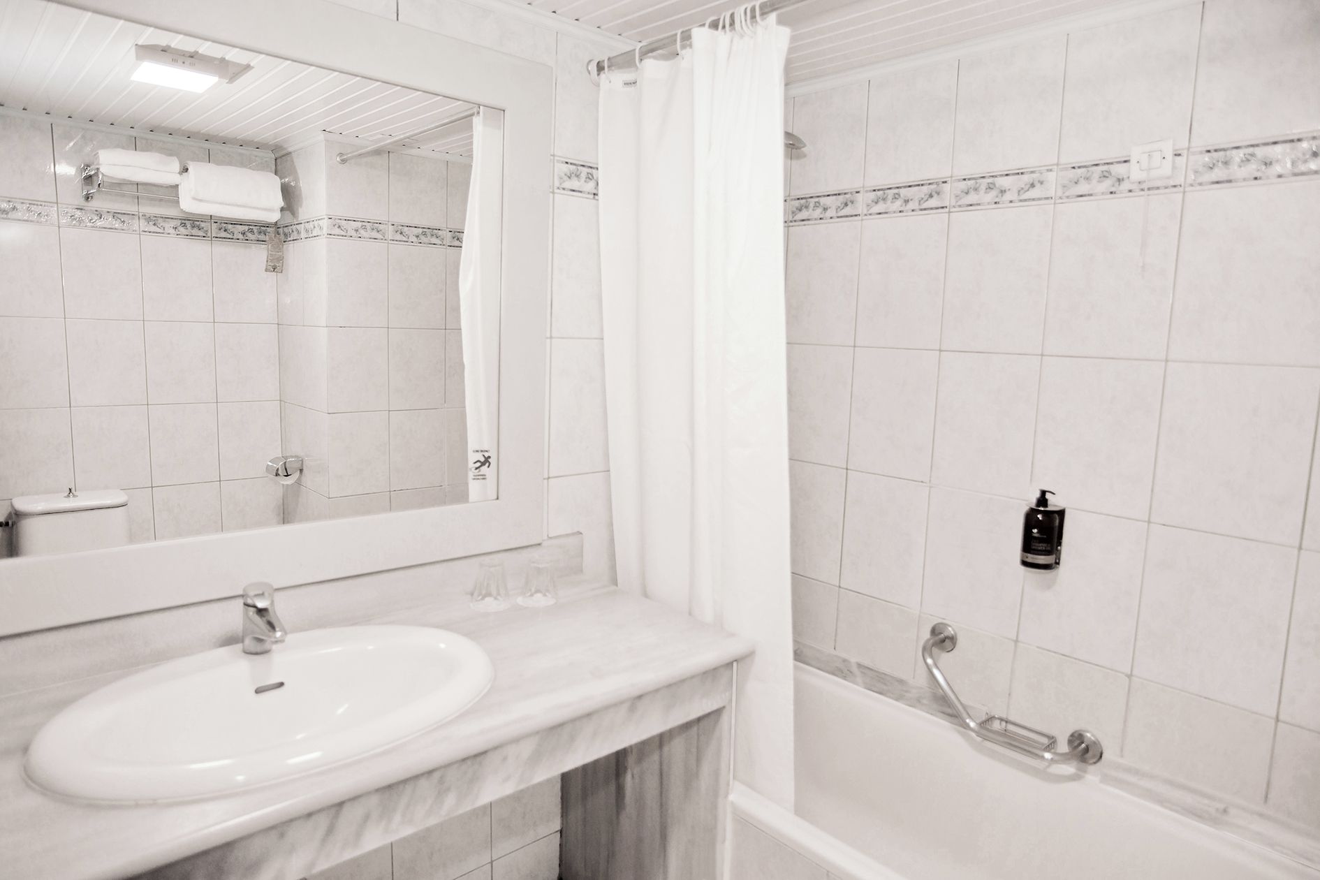 A bathroom with a white sink, mirror, and shower area.