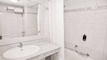 A bathroom with a white sink, mirror, and shower area.