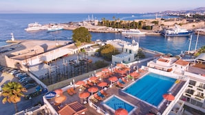 A hotel with a swimming pool, outdoor seating, and a view of the sea.