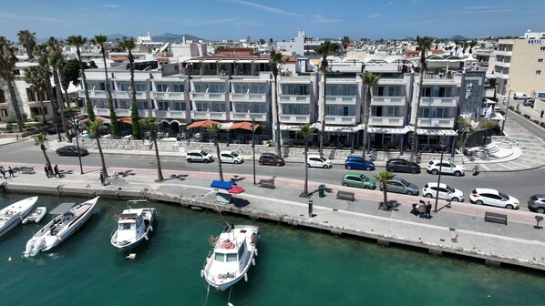 A marina with boats docked, a waterfront promenade with benches, and modern buildings in the background.