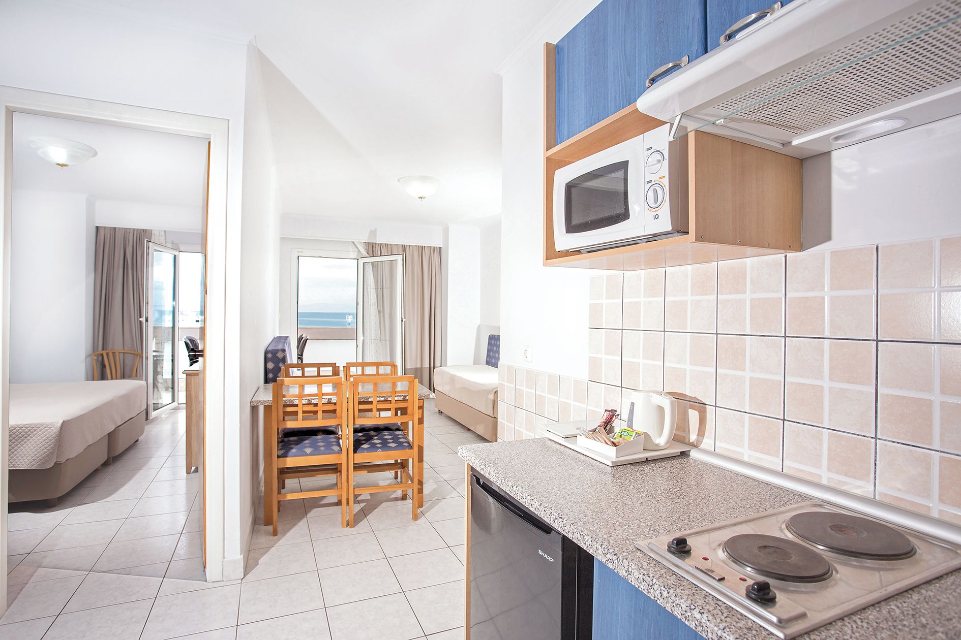 A compact kitchen with a microwave, stove, and a dining area with chairs.