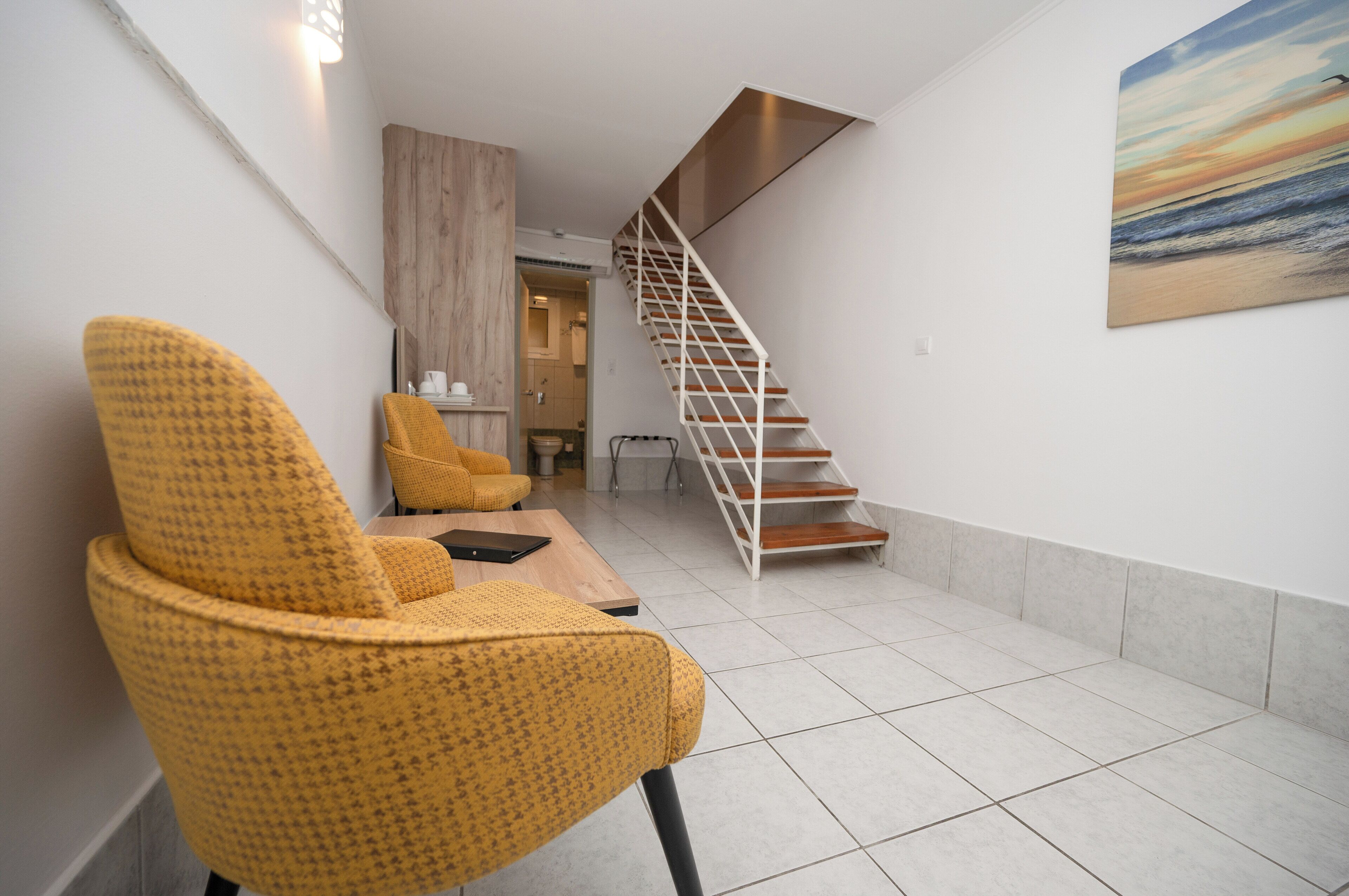 A modern interior with a yellow chair, a staircase, and a painting on the wall.