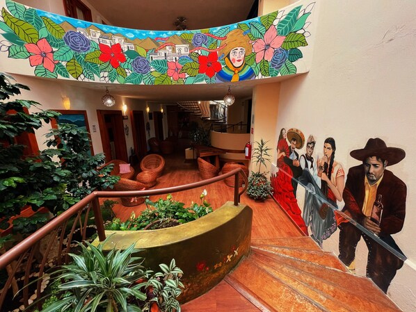 A staircase with a mural, wicker furniture, and indoor plants.