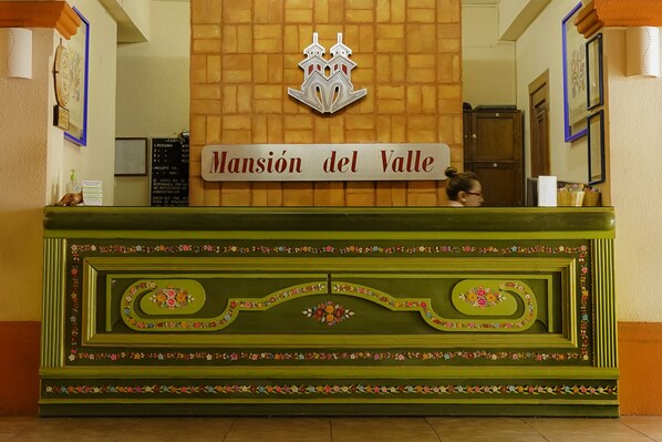 Una mesa de recepción con un cartel que dice "Mansión del Valle" y un logotipo encima.