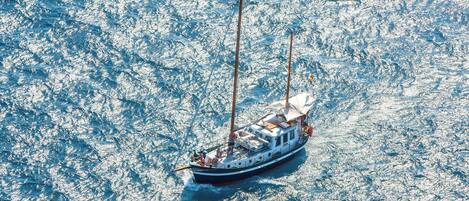 A boat with a cabin and two masts sailing on a body of water.