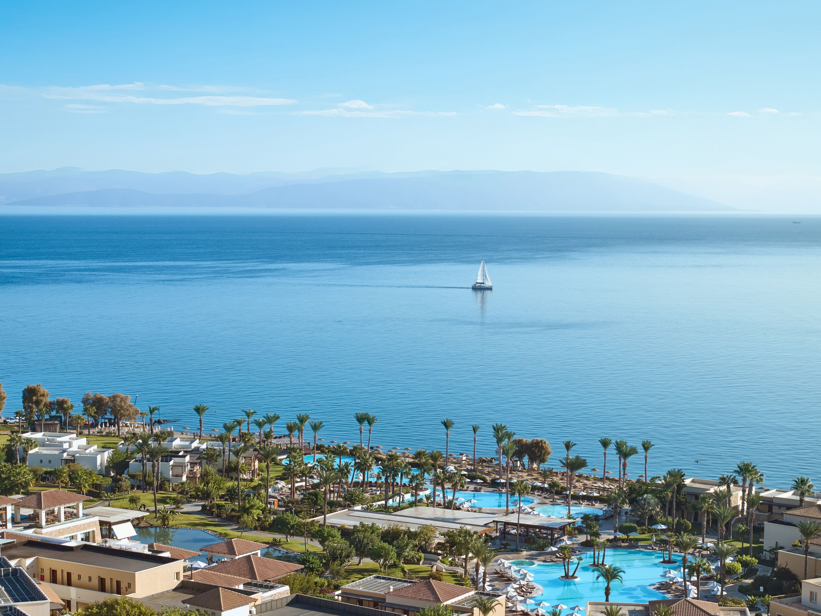 Un resort con varias piscinas, palmeras y vistas al mar.