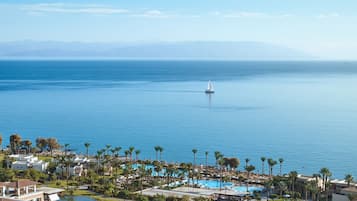 Un resort con varias piscinas, palmeras y vistas al mar.