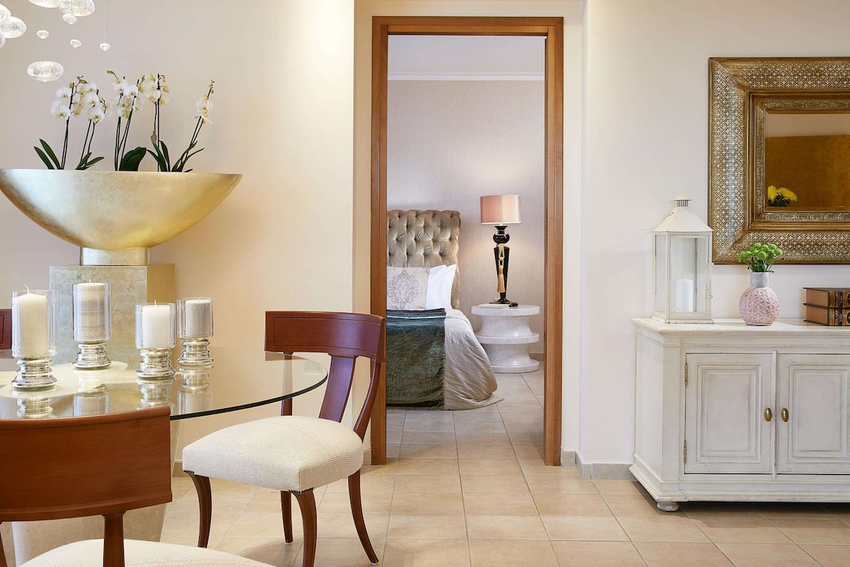 Een hotelkamer met een eethoek, een grote spiegel en zicht op een andere kamer.