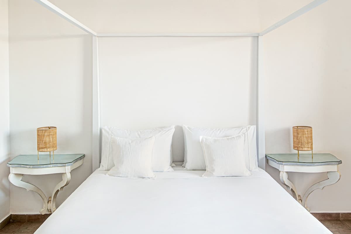 Een slaapkamer met een groot bed, twee nachtkastjes en een wit hoofdeinde.