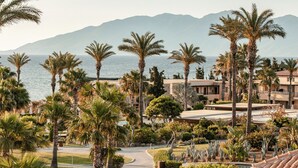 Ein Resort mit Palmen, einem Pool und Blick auf Meer und Berge.