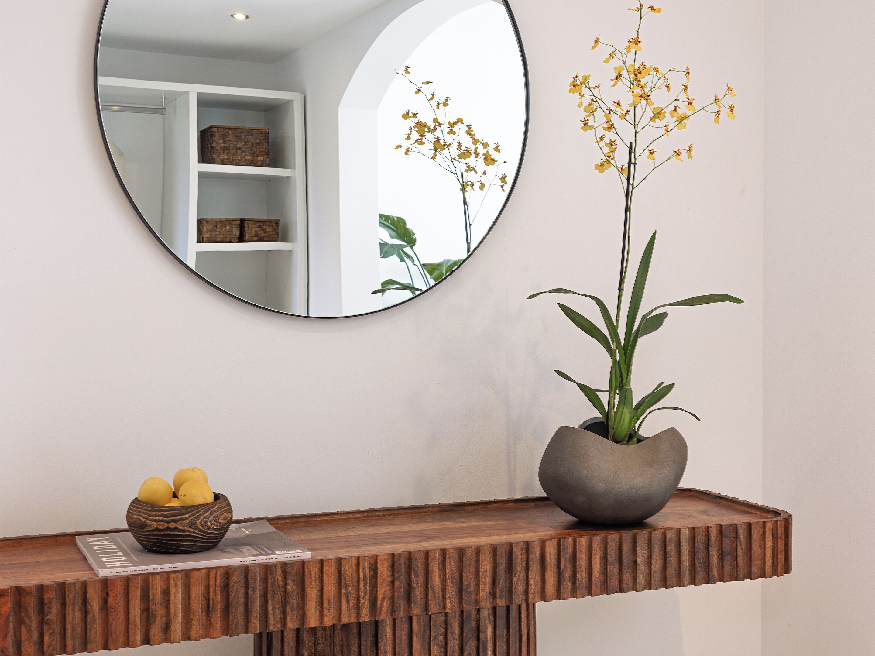 A wooden console table with a bowl of lemons and a potted plant.