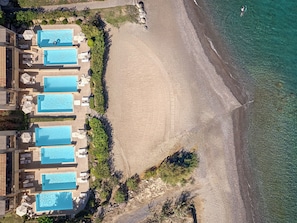 Vista aérea de um resort com várias piscinas, uma praia de areia e águas azul-claras.