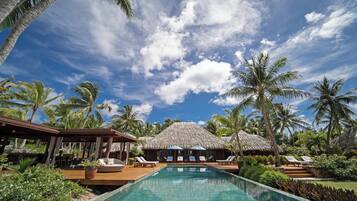 A pool area with lounge chairs and a thatched-roof structure.