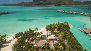 An aerial view of a tropical resort with overwater bungalows, a beach, and a mountain in the background. - Four Seasons Resort Bora Bora (Bora Bora)